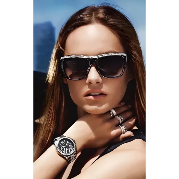 MICHAEL KORS MK5829-3 A person with long brown hair wears multiple rings and a stylish black watch while posing with a scenic background.